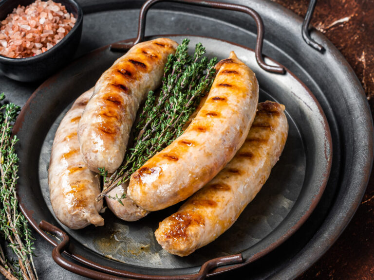 BBQ Fried Bratwurst and Chorizo sausages with herbs on a steel serving tray. Dark background. Top view. Copy space.