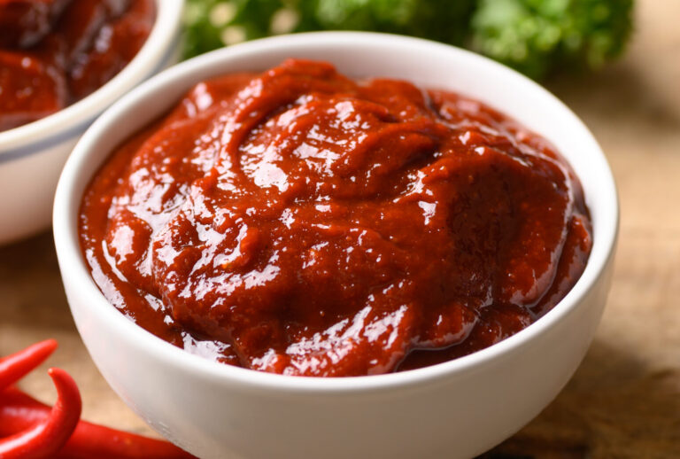 Korean gochujang (red chili paste) in bowl on wooden table, spicy and sweet fermented condiment in Korean food