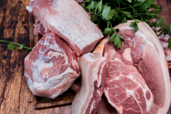 Many pieces of fresh pork meat on a wooden cutting board