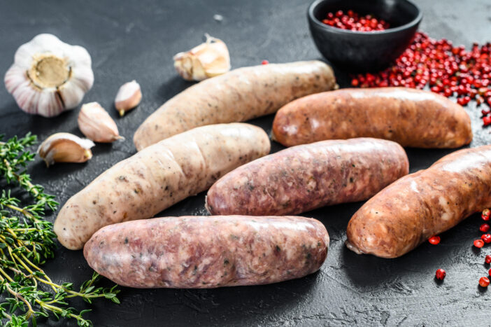 Assorted fresh raw sausages with spices.  Black background. Top view.