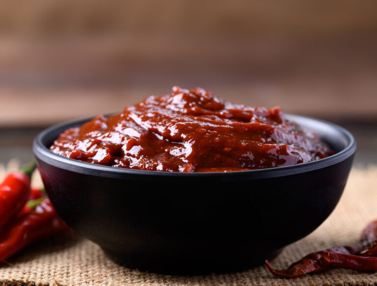 Gochujang (red chili paste) on wooden background, spicy and sweet fermented condiment in Korean food