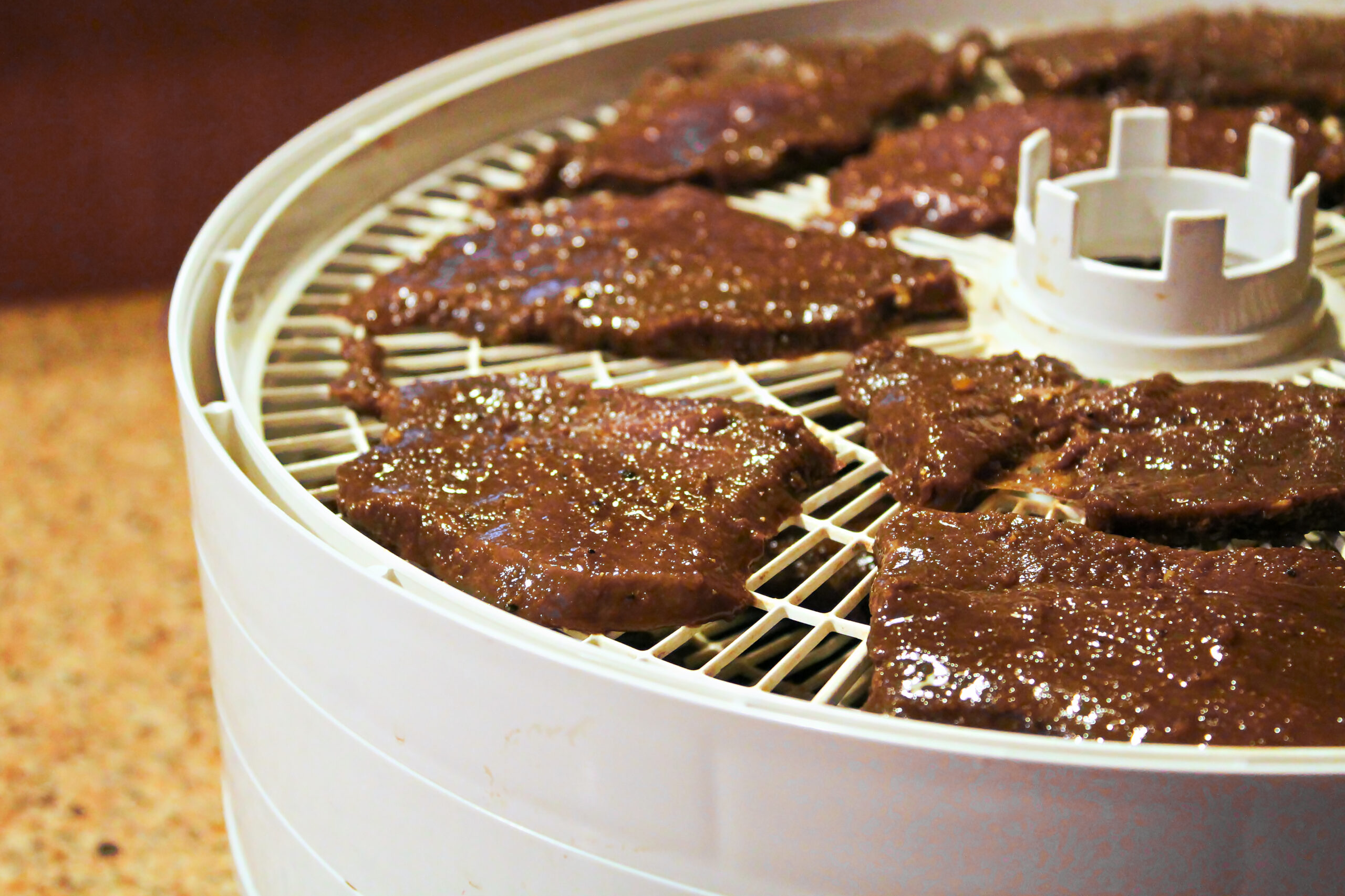 Meat slices laid out on a dehydrator to be made into deer jerky.