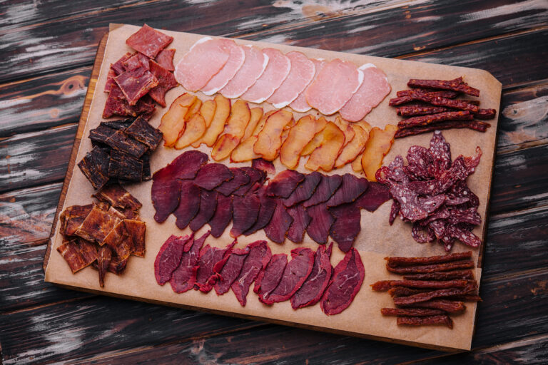 various jerky or dried meats and sausage on a board