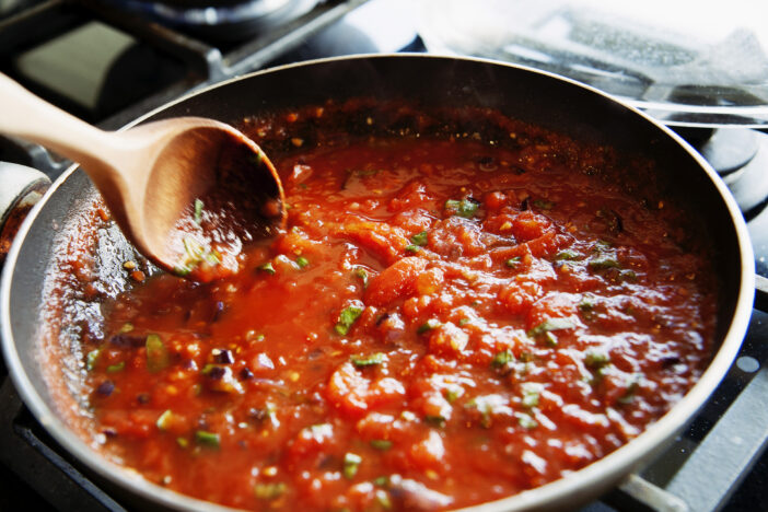 Vilnius, Lithuania - June 17, 2011: preparing of a homemade tomato sauce in a frying pan from fresh tomatoes.