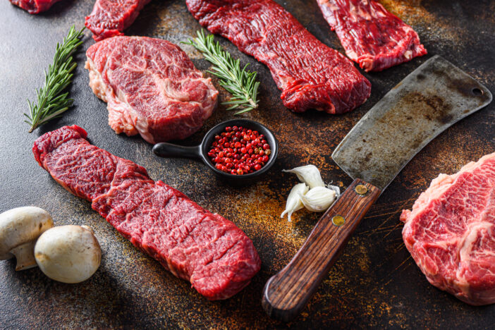 Side view Close up machete Steak, Flank steak, cut near denver alternative beef steak and a cleaver butcher meat knife   a rustic metall background.