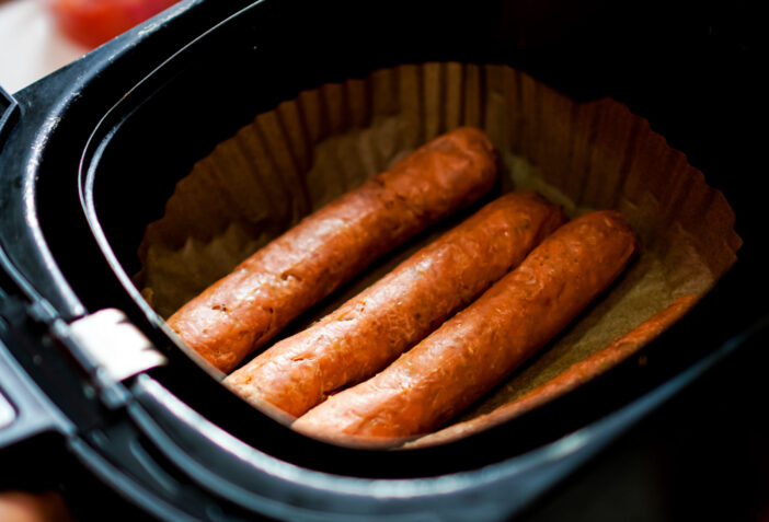 The picture shows plant-based sausages that are baked in an electric fryer to ensure they are cooked just right.