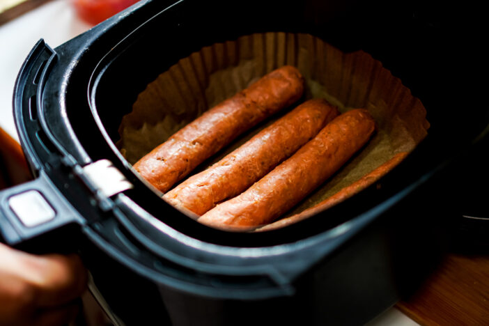 The picture shows plant-based sausages that are baked in an electric fryer to ensure they are cooked just right.