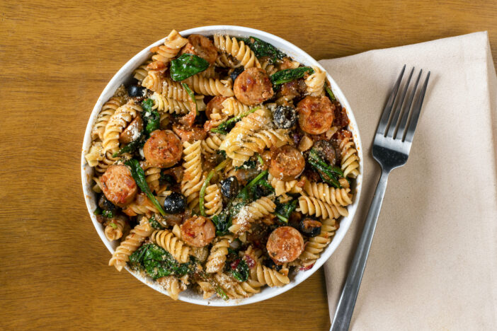 rotini pasta served with italian sausage and sauteed spinach.