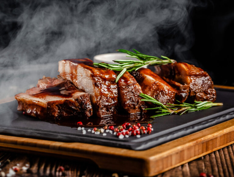 American food concept. Grilled pork ribs with grilled sauce, with smoke, spices and rosemary. Background image. copy space