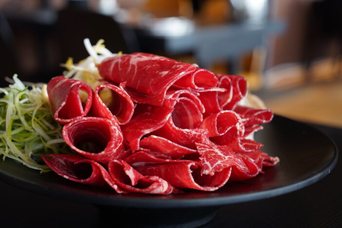 Raw red meat for shabu-shabu is thinly sliced and rolled into a round shape.