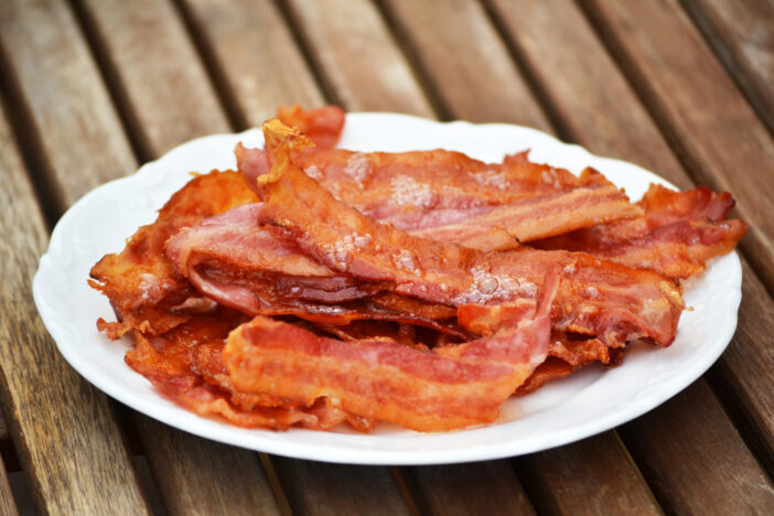 A white plate with bacon on a wooden table