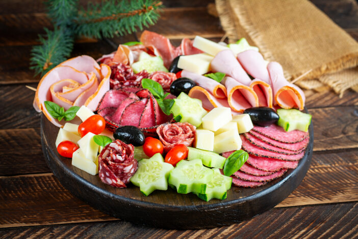 Colorful charcuterie boards and boxes vegetables, meat and cheese.  Assortment of tasty appetizers or antipasti.