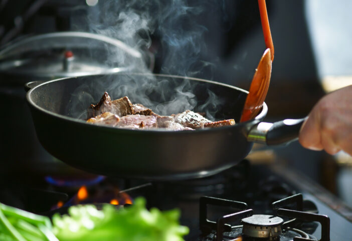 Man cooks meat in a frying pan