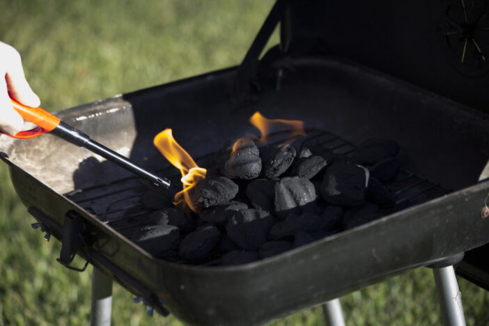 Person starting barbecue grill flame