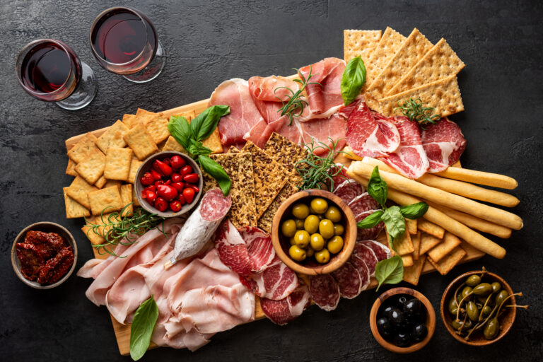 Appetizers with differents antipasti, charcuterie, snacks and red wine. Sausage, ham, tapas, olives and crackers for buffet party. Top view, flat lay