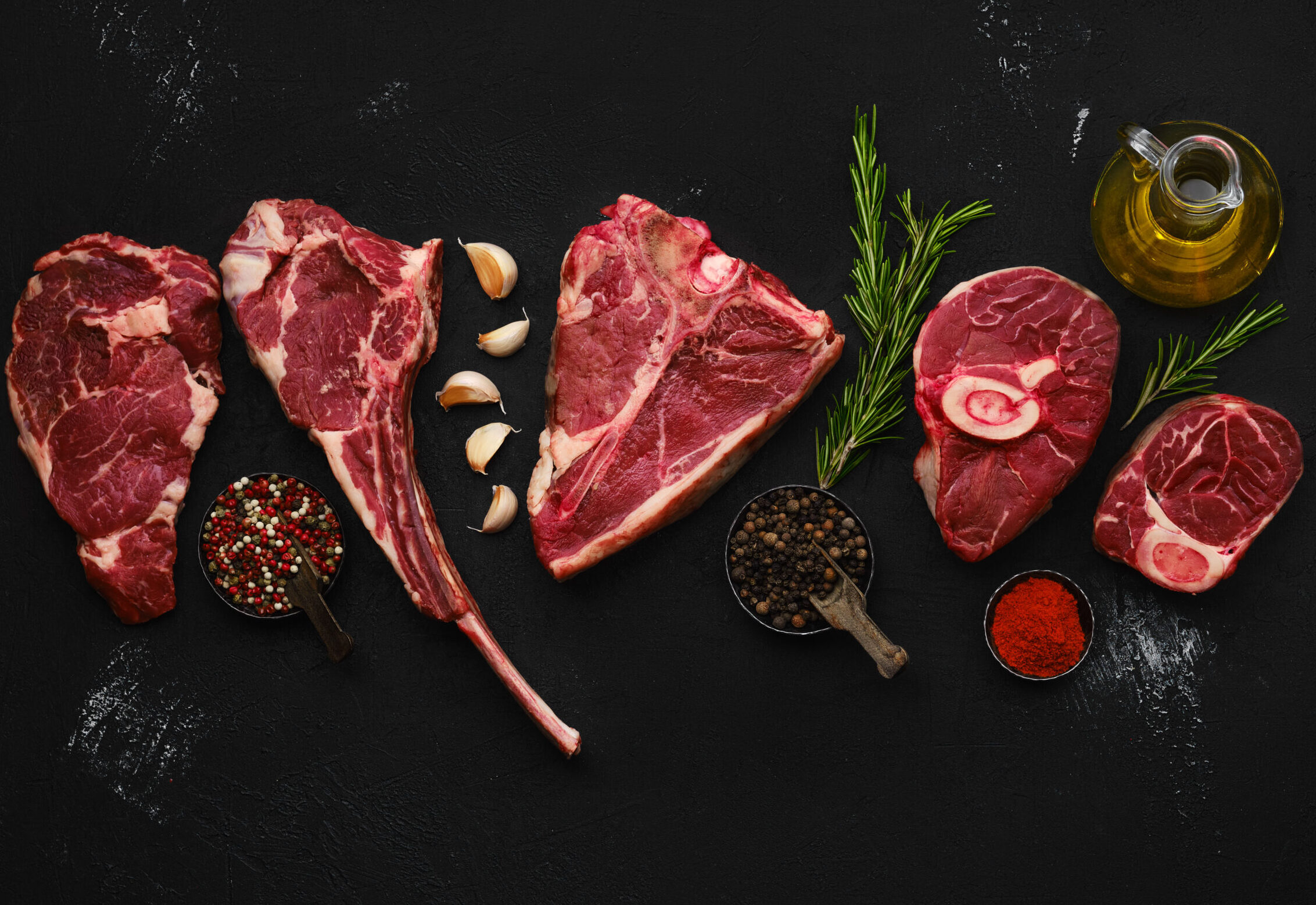 Overhead composition with raw prime beef cuts - porter house, cowboy steak, ossobuco, ribeye and tri-tip roast