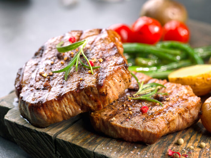 grilled beef steaks on wooden cutting board