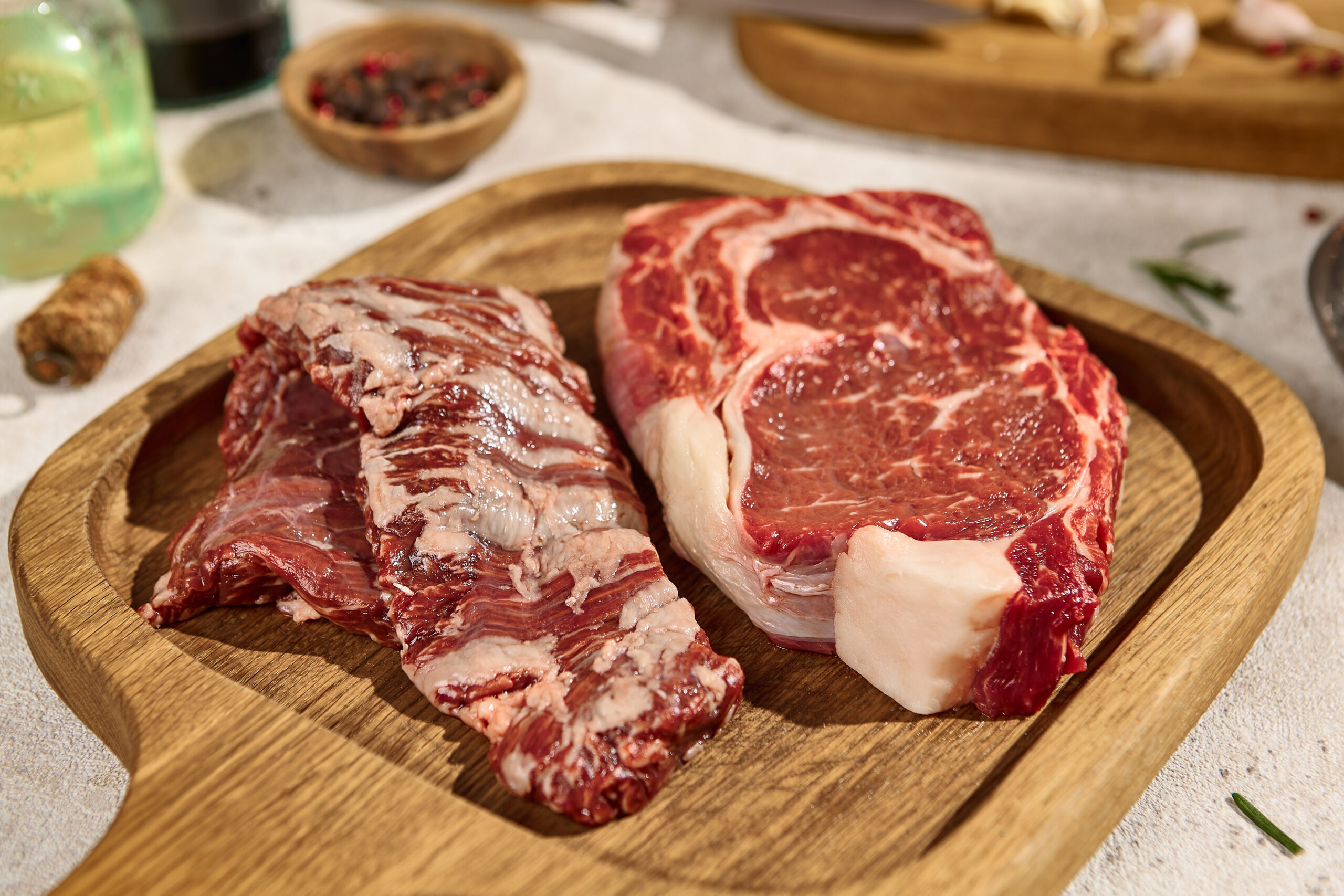 Fresh Raw Steaks on Wooden Board Under Sunlight New York Strip and Chuck Roll Cuts for Summer BBQ.