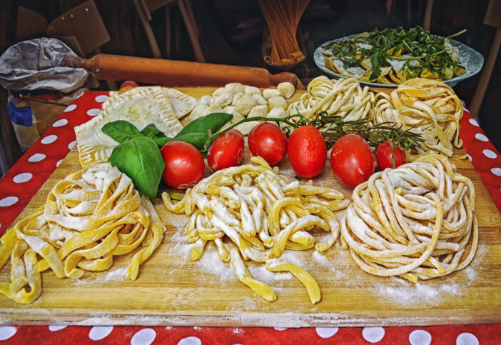 A summer  dinner .Pasta , pizza  and homemade food arrangement outside a restaurant in Rome  .Tasty and authentic Italian food ,Italy
