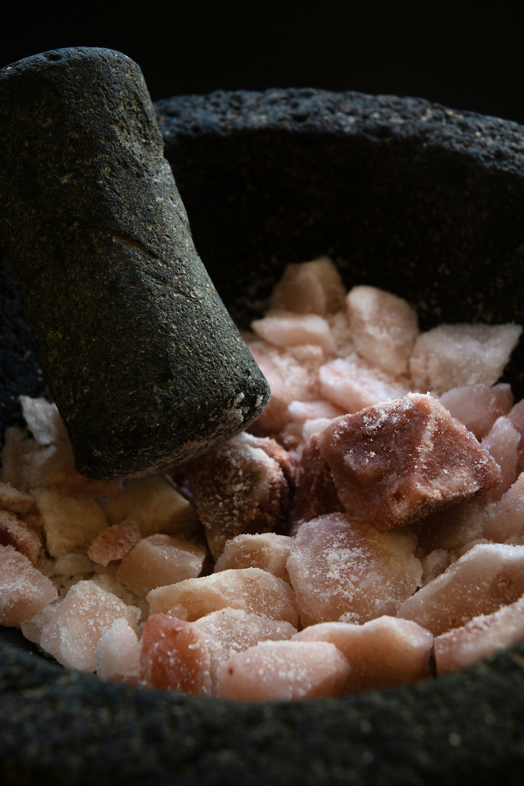 Grinding lumps of pink himalayan salt in a traditional mexican mortar.