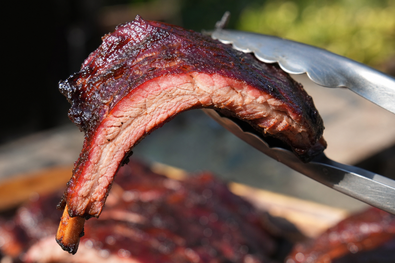 Perfectly cooked ribs being bend tested with tongs showing proper doneness