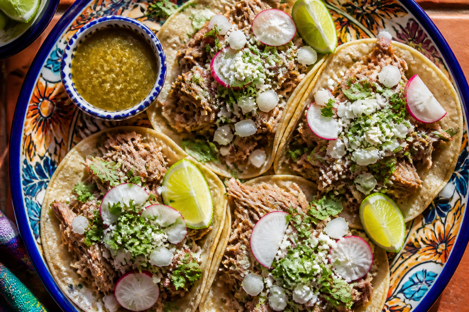 Pulled pork tacos on corn tortillas with cilantro, onions, queso fresco and lime