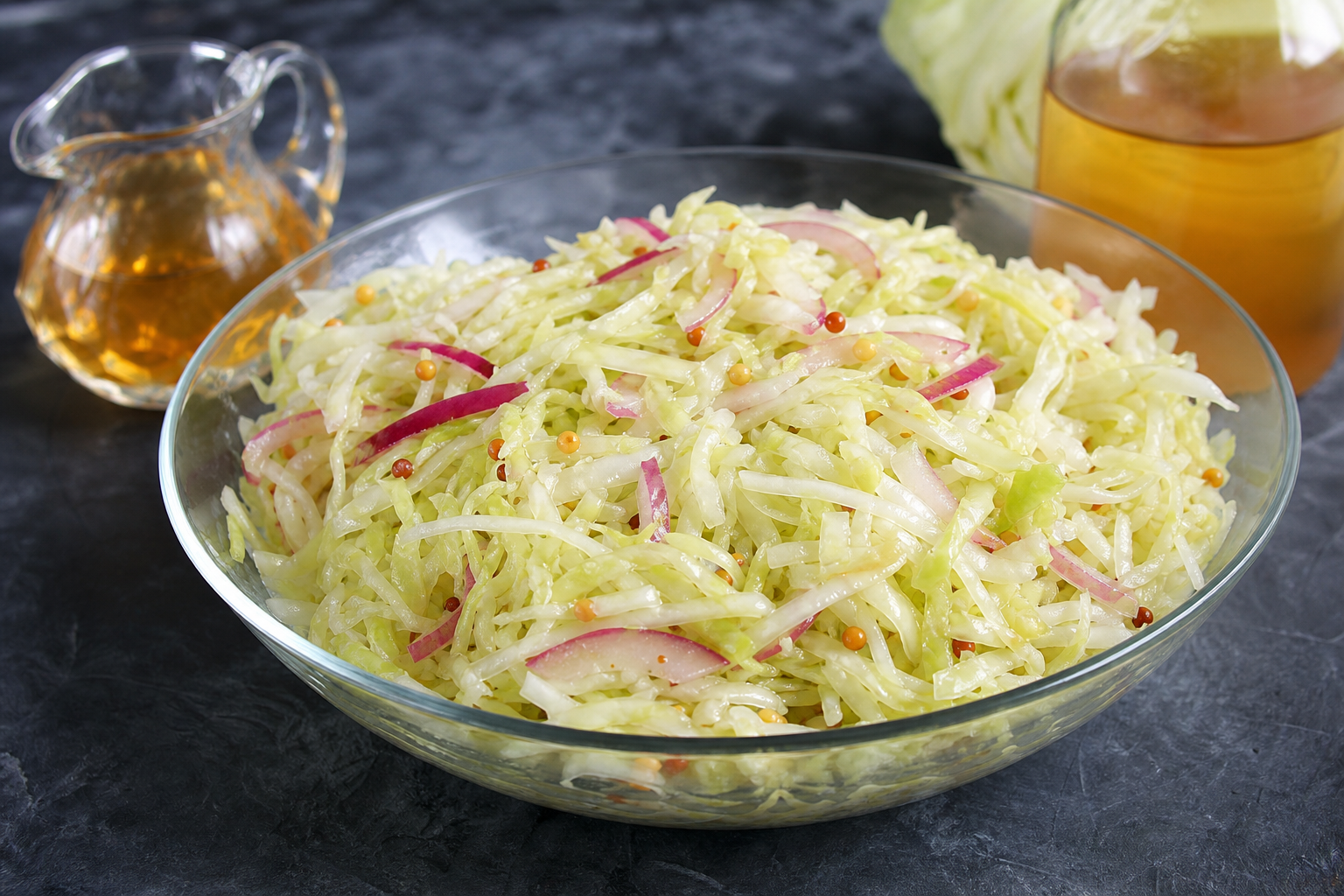 10 Coleslaw Ideas That Go Beyond the Basics 15 Glass bowl of Carolina vinegar coleslaw with pale green cabbage, red onion, and mustard seeds