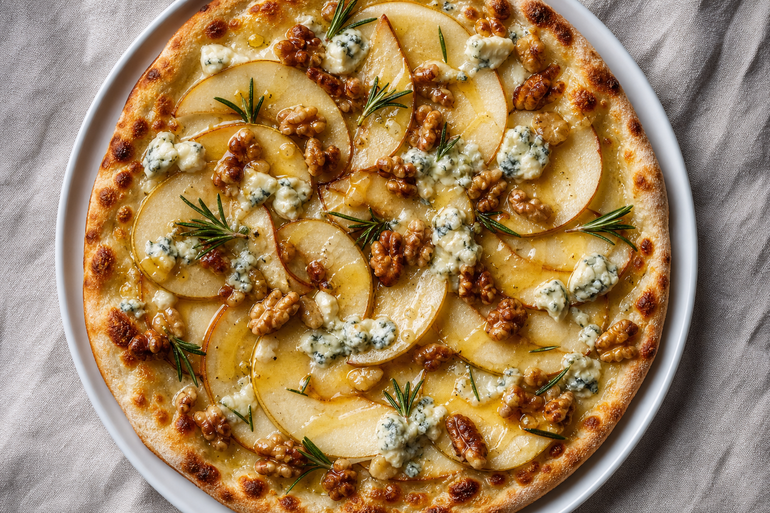 Sweet and savory caramelized pear and gorgonzola pizza with candied walnuts and honey drizzle on a white plate