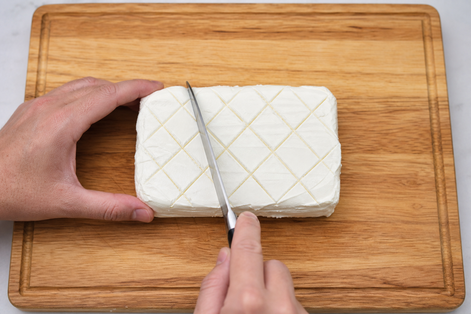 Why Your Smoked Cream Cheese Cracks and How to Fix It 11 Hands scoring a crosshatch pattern into a block of cream cheese with a knife