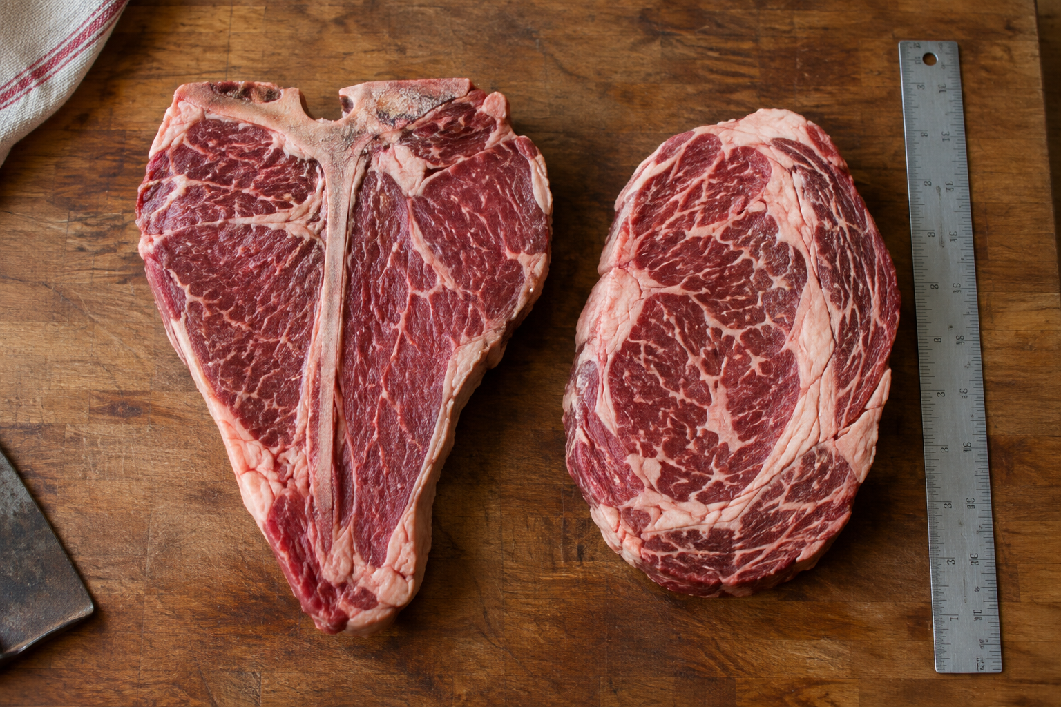 Bone-in T-bone steak next to boneless ribeye steak for portion comparison