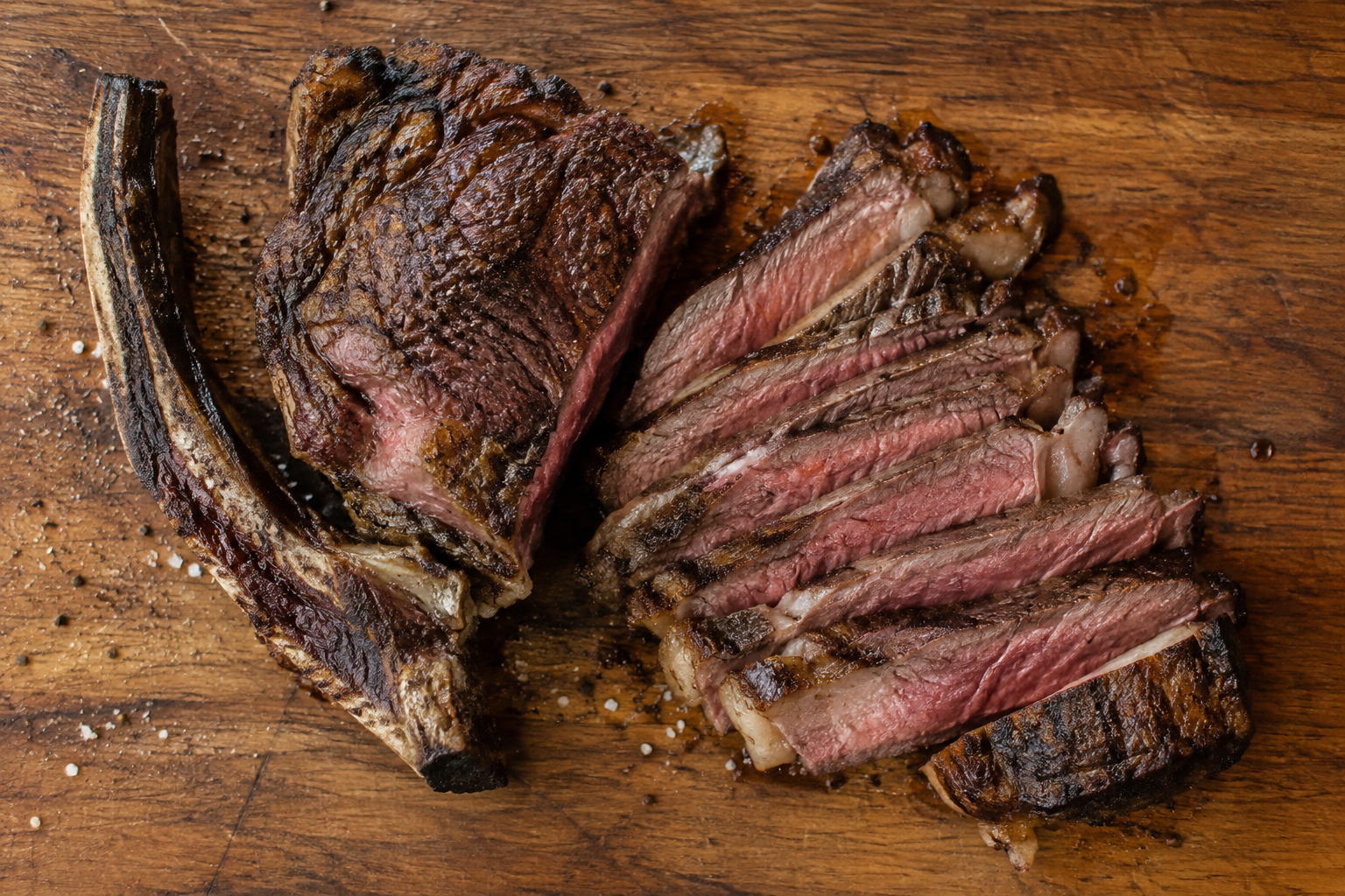 Bone-In Ribeye vs Boneless Ribeye: Which Gives You More Steak? 9 Sliced cooked ribeye steak with bone separated to show edible meat yield