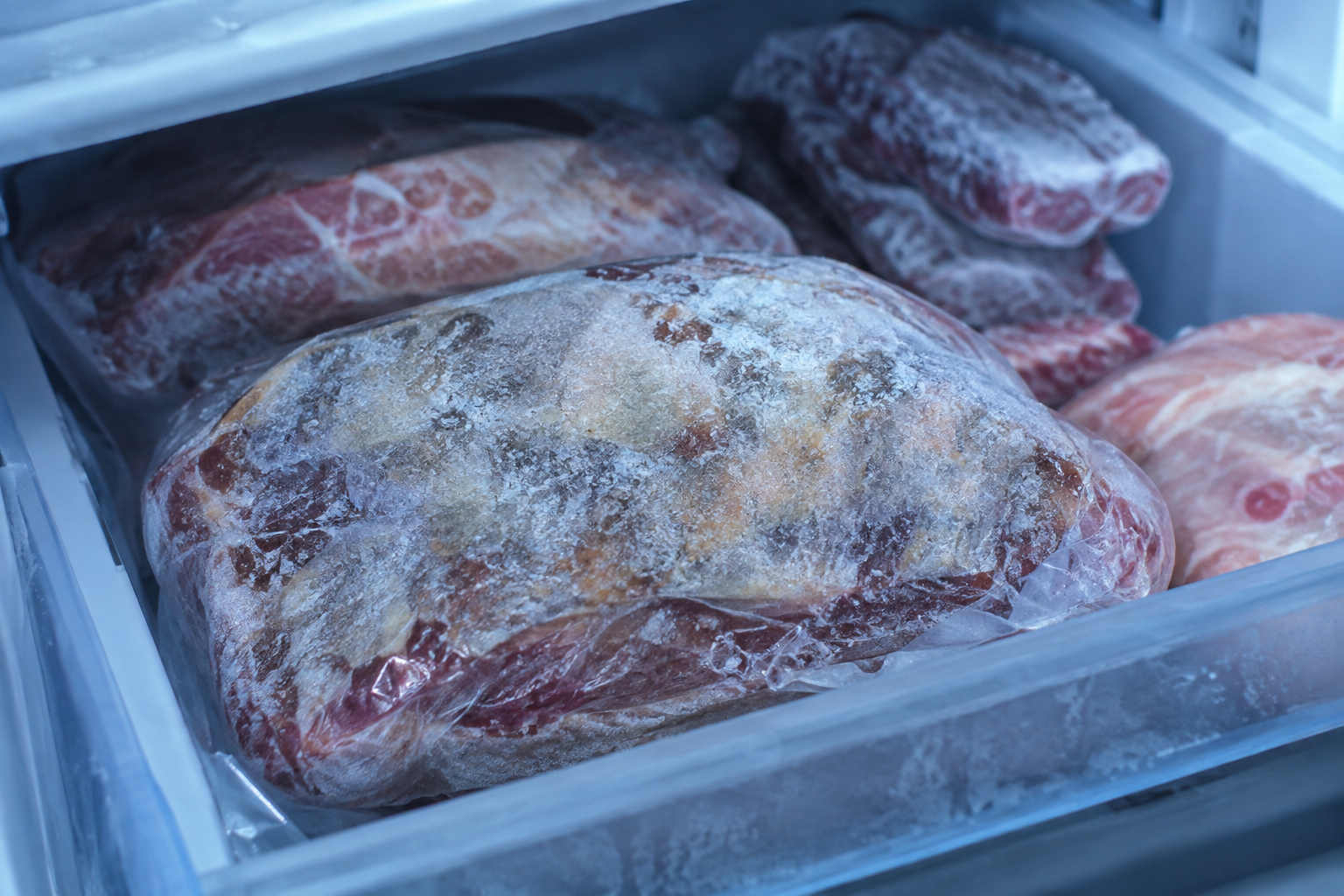 Frozen meat package showing signs of freezer burn in a freezer drawer